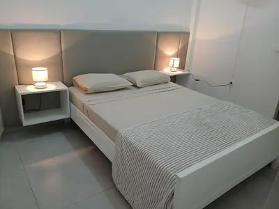 a white bed with two lamps on two tables at Núria's Apartment in Mindelo