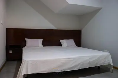 a bedroom with a large white bed with a wooden headboard at Helton´s Residence in Praia