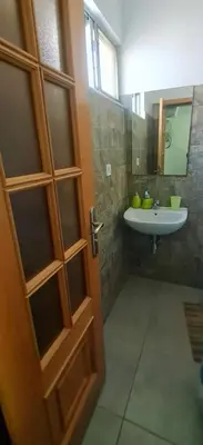 a bathroom with a sink and a bathroom door at Helton´s Residence in Praia