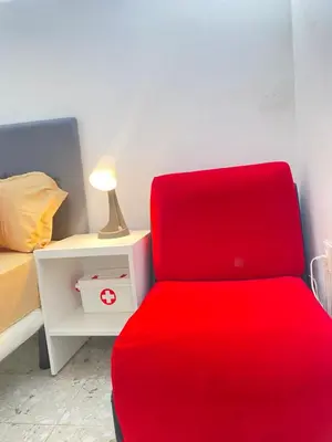 a red chair in a bedroom with a bed and a lamp at Best Rooms- Quarto 4 Plateau in Praia