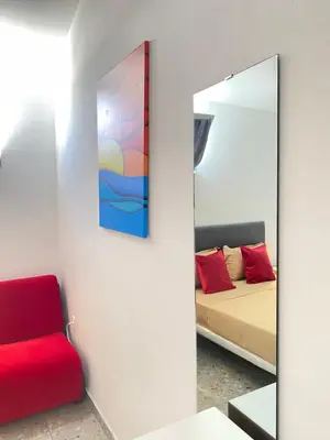 a mirror in a room with a bed and a red chair at Best Rooms- Quarto 4 Plateau in Praia