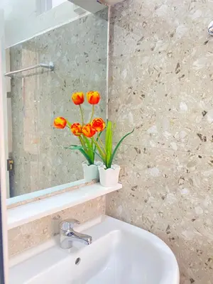 a bathroom with a sink and a vase with orange flowers at Best Rooms- Quarto 4 Plateau in Praia