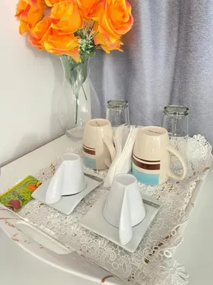 a table with plates and cups and a vase with orange roses at Best Rooms- Quarto 2 Plateau in Praia