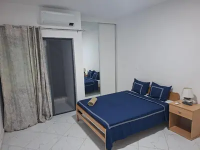 a bedroom with a bed with blue sheets and a table at Figo Apartamentos Cidadela Comfort Flats in Praia