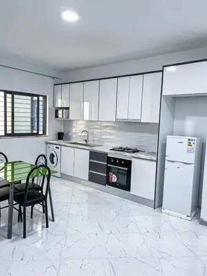 a kitchen with white cabinets and a table and a refrigerator at Figo Apartamentos Cidadela Comfort Flats in Praia