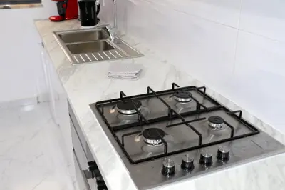 a stove top in a white kitchen with a sink at Figo Apartamentos Cidadela Comfort Flats in Praia