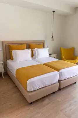 a bedroom with a large bed with two chairs at Santa Cruz Boutique Hotel in Mindelo