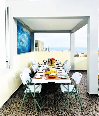 a dining room with a long table and white chairs at Casa BB&Djassi - ROOMS in Ponta do Sol