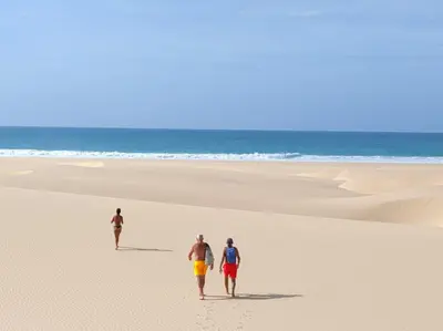 three people walking on a beach with the ocean in the background at Casa Veronica Boavista in Sal Rei
