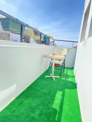 a table and chair on a balcony with green grass at Best Rooms - Quarto 1 Plateau in Praia