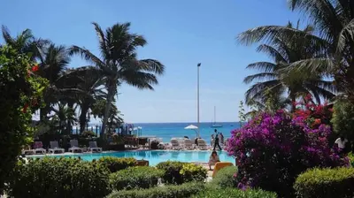 a swimming pool with palm trees and the ocean at Beach front ocean view Porto Antigo2 Santa Maria in Santa Maria