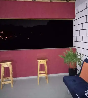 a room with two stools and a pink wall at Casa Familiar Pôr do Sol in Ribeira Grande