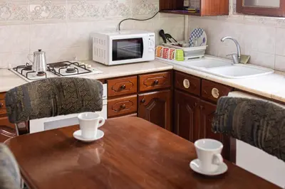 a kitchen with a wooden table and a microwave at Maya Apartments in Mindelo
