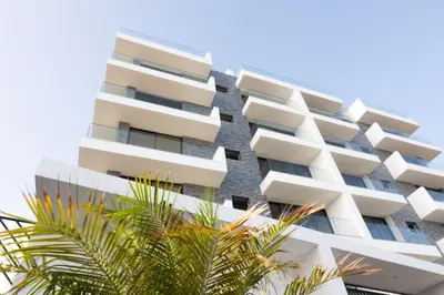 a tall white building with palm trees in front of it at 3 bdr aprt, best seaview, rooftop pool - LCGR in Praia