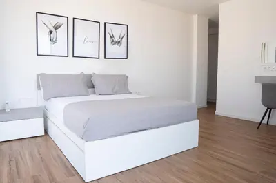 a white bed in a white bedroom with three pictures on the wall at 3 bdr aprt, best seaview, rooftop pool - LCGR in Praia