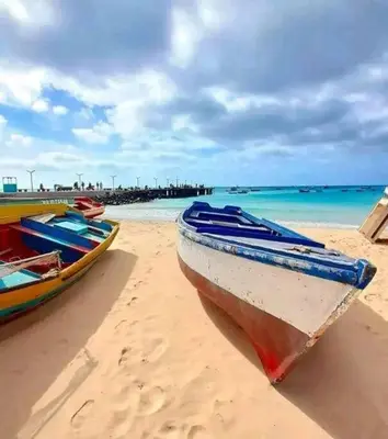 two boats sitting on a beach with the ocean at Lovely Apartment In Mindelo City Center in Mindelo