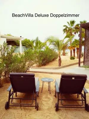 two chairs and a table in the sand with palm trees at Luxury Beach Villa, Praia de Chaves, Boa Vista in Boa Ventura