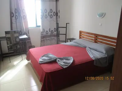 a bedroom with a red bed with a bow on it at Recanto Verde Cara in Mindelo