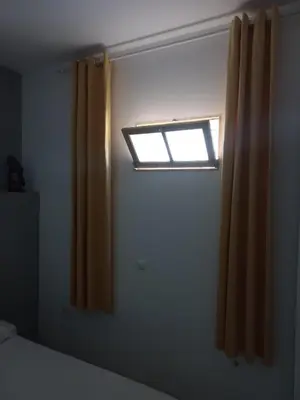 a bedroom with a window and a curtain at Kaza Jindung in Mindelo
