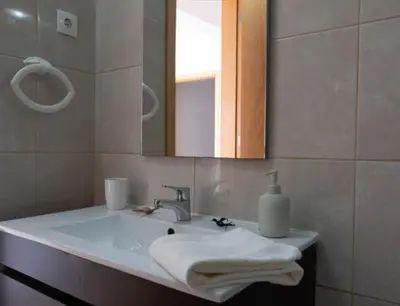 a bathroom with a sink and a mirror and towels at Casa Maria Apartments in Santa Maria