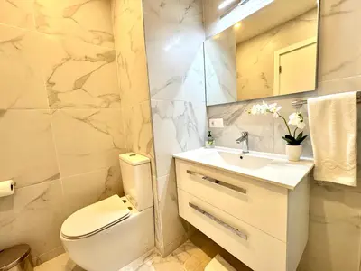 a white bathroom with a toilet and a sink at SunSet in Santa Maria