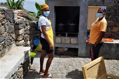 two women wearing masks in front of an oven at Pousada Dragoeiro Monte Joana Santo Antão in Ribeira Grande