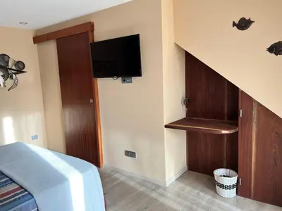 a bedroom with a bed and a staircase with a tv at Orietta Residencial in Mindelo