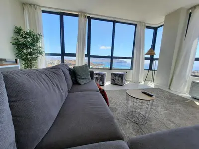 a living room with a gray couch and large windows at Bellavista in Mindelo