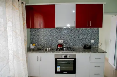 a kitchen with red cabinets and a sink at Comfortable and Cozy Apartments in Praia