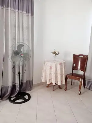 a room with a floor fan and a table with a chair at Kaza Mamai di Fora in Calheta de São Miguel