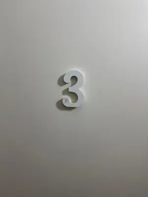 a metal number three on a white wall at KAZARÃO DI MAVETE- Guesthouse in Praia