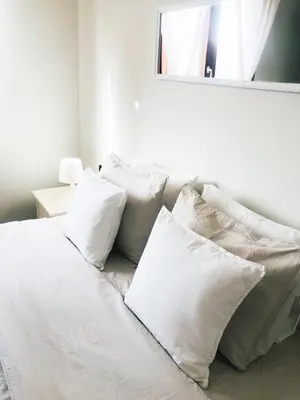 a pile of white pillows on a bed with a mirror at Boavista Beach Apartment in Sal Rei