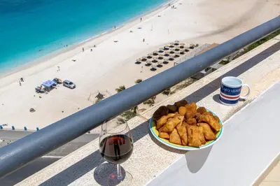 a bowl of food and a glass of wine next to a beach at Sky Mariposa sospesa sul mare in Mindelo