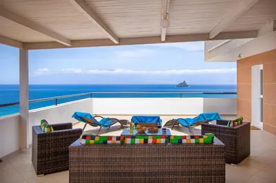 a balcony with a table and chairs and the ocean at Sky Mariposa sospesa sul mare in Mindelo