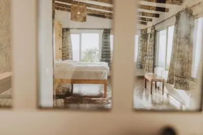 a mirror in a room with a bed and a table at Strela Mountain Lodge in Tarrafal