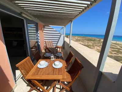 a wooden table and chairs on a balcony with the beach at Corallo Beach Front Apartments - By Bobbywashere in Santa Maria