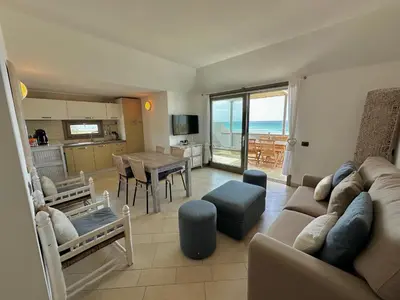 a living room with a couch and a dining room with the ocean at Corallo Beach Front Apartments - By Bobbywashere in Santa Maria