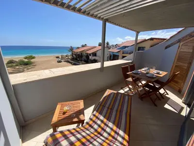 a balcony with a table and chairs and the ocean at Corallo Beach Front Apartments - By Bobbywashere in Santa Maria