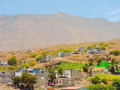 a village on a hill with a mountain in the background at Pousada Cantinho de Preta in Seladinha