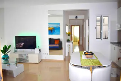 a white living room with a television and a table at Taninho in Santa Maria