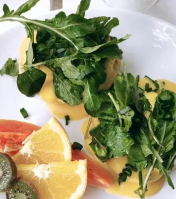 a white plate with greens and citrus fruits on it at Syds Beach House in Praia