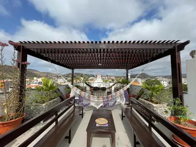 a wooden table on a balcony with a pergola at Hotel Viajante in Tarrafal