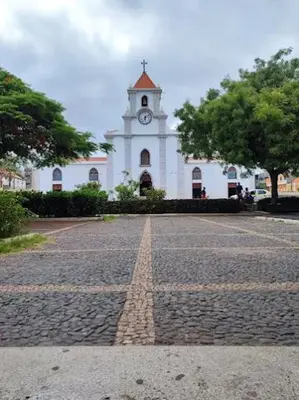 a white building with a clock tower on a street at Hotel Viajante in Tarrafal