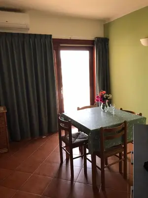 a dining room with a table and chairs and a window at studio's Porto Antigo 2 in Santa Maria