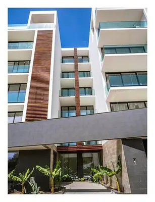 a large white building with palm trees in front of it at Filomena Apartments BOHÈME in Mindelo