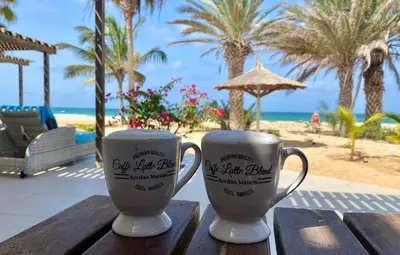 two coffee mugs sitting on a wooden table near the beach at Vila Mare - Praia de Chaves frontline in Cabeçadas