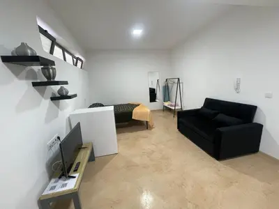 a living room with a black couch and a bed at Tia Nita Apartamentos in Mindelo