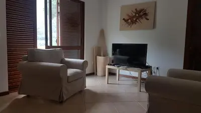 a living room with a chair and a television at Residencial Lela d'Fermina in Pombas