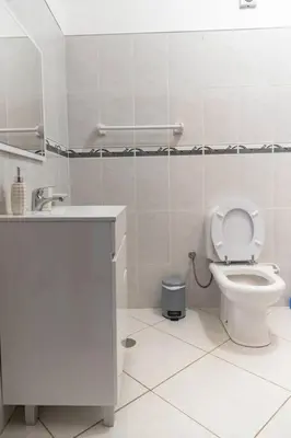 a white bathroom with a toilet and a sink at 3 bedroom apt, Exterior POOL , Cidadela - LCGR in Praia