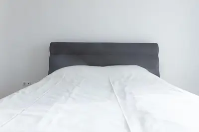 a bed with white sheets and a black headboard at 3 bedroom apt, Exterior POOL , Cidadela - LCGR in Praia
